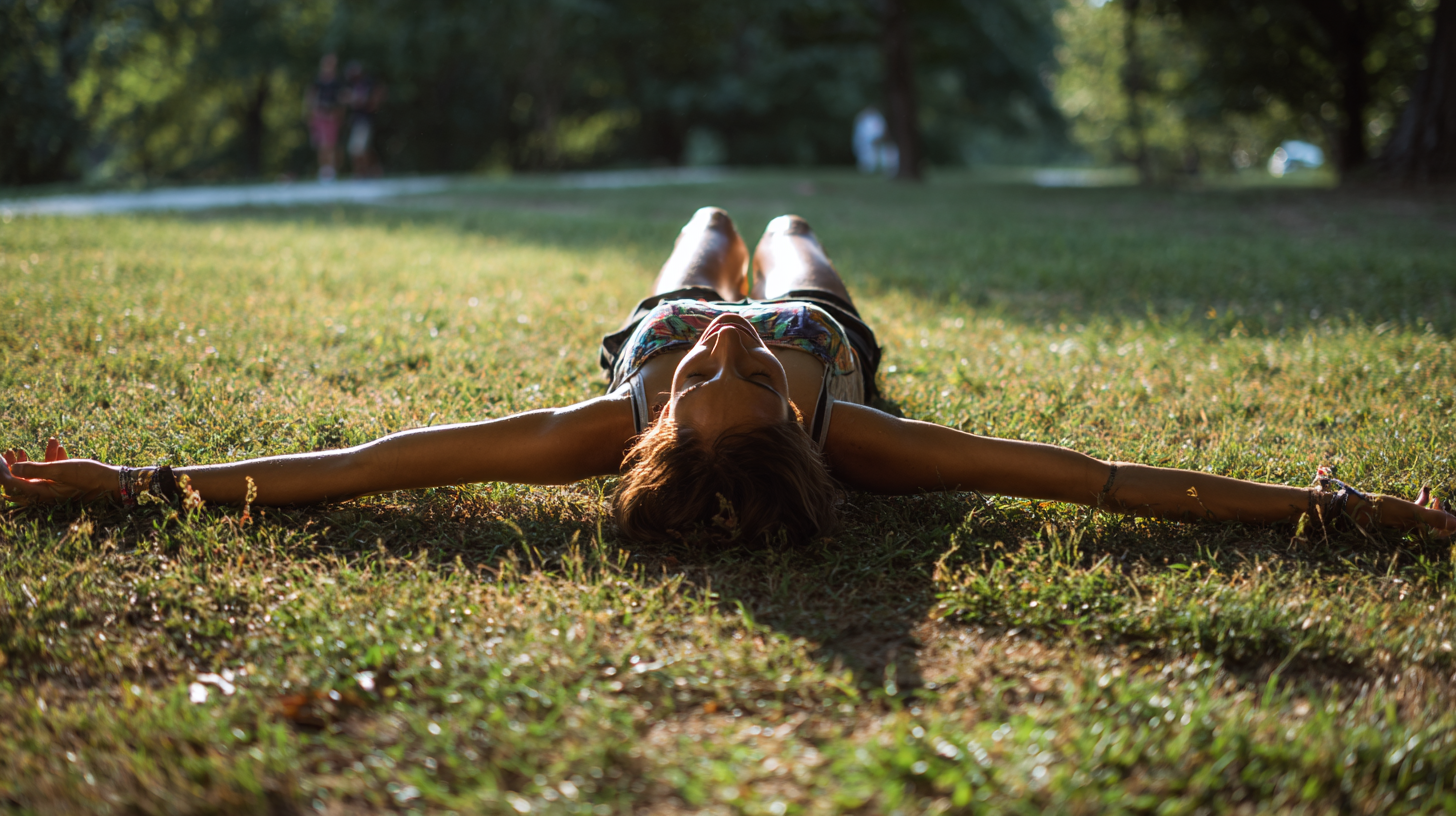 A person in a park laying on their back in an outstretched pose